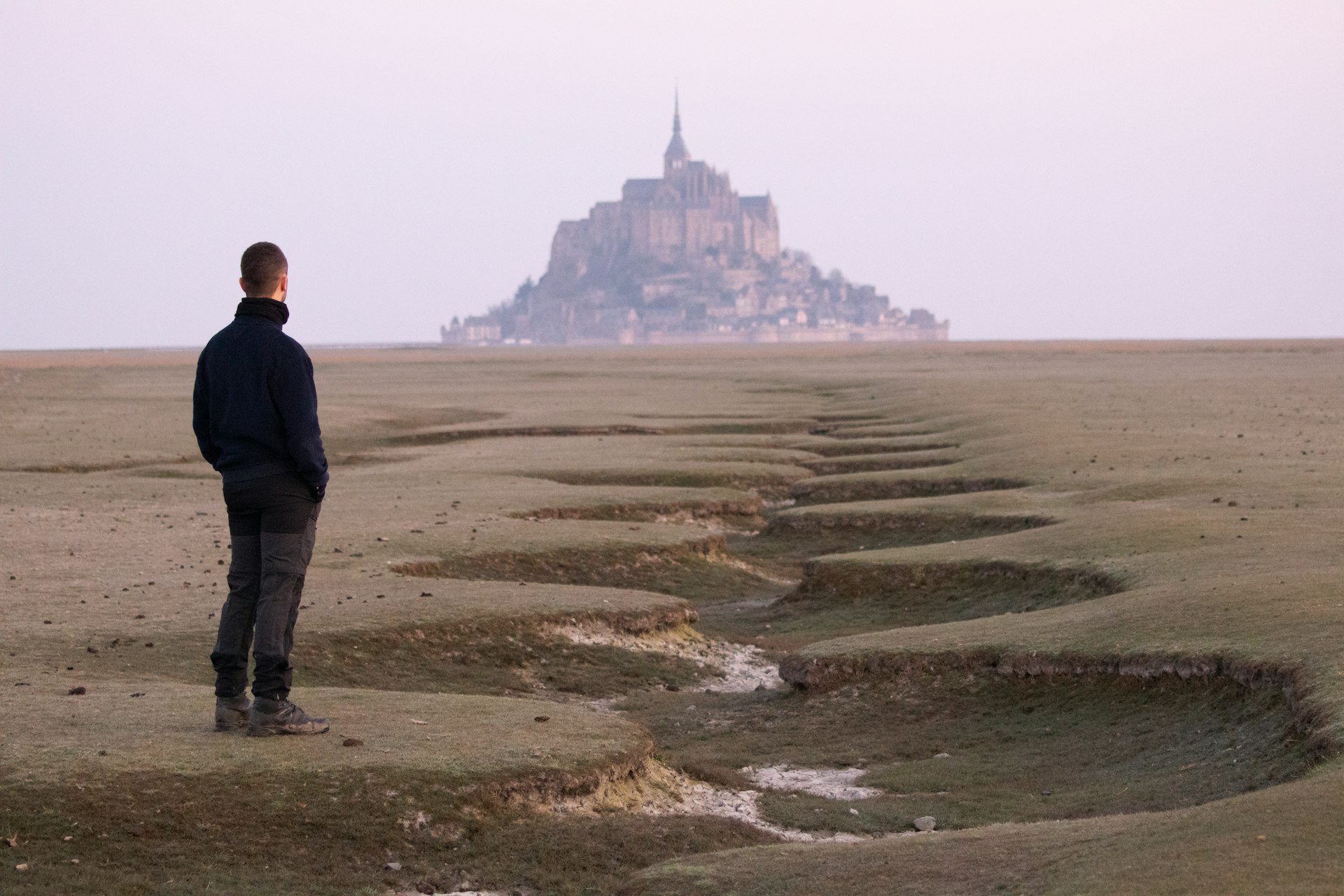 a man standing in a field with a castle in the background